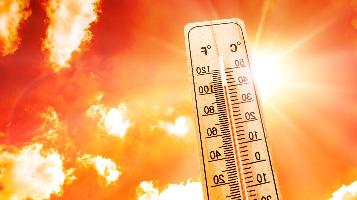 Thermometer atop a background of an orange sky with bright sun.